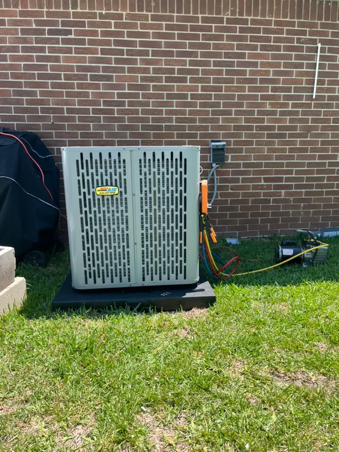 Sweet Georgia technician's gauges connected to a newly installed residential condensing unit at a brick home near Metter