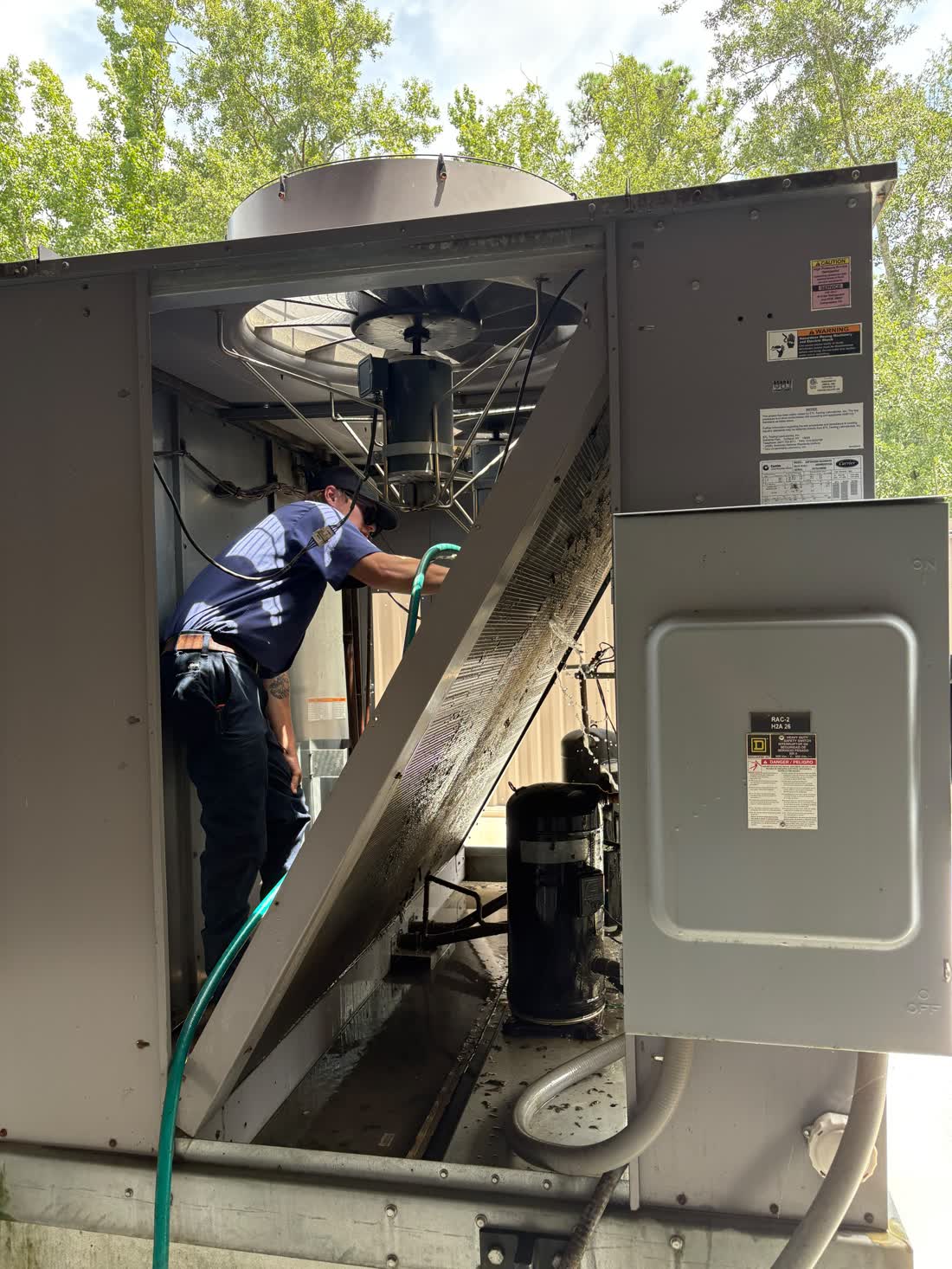 Sweet Georgia technician washing the condenser coil on a rooftop package unit at a Statesboro commercial building