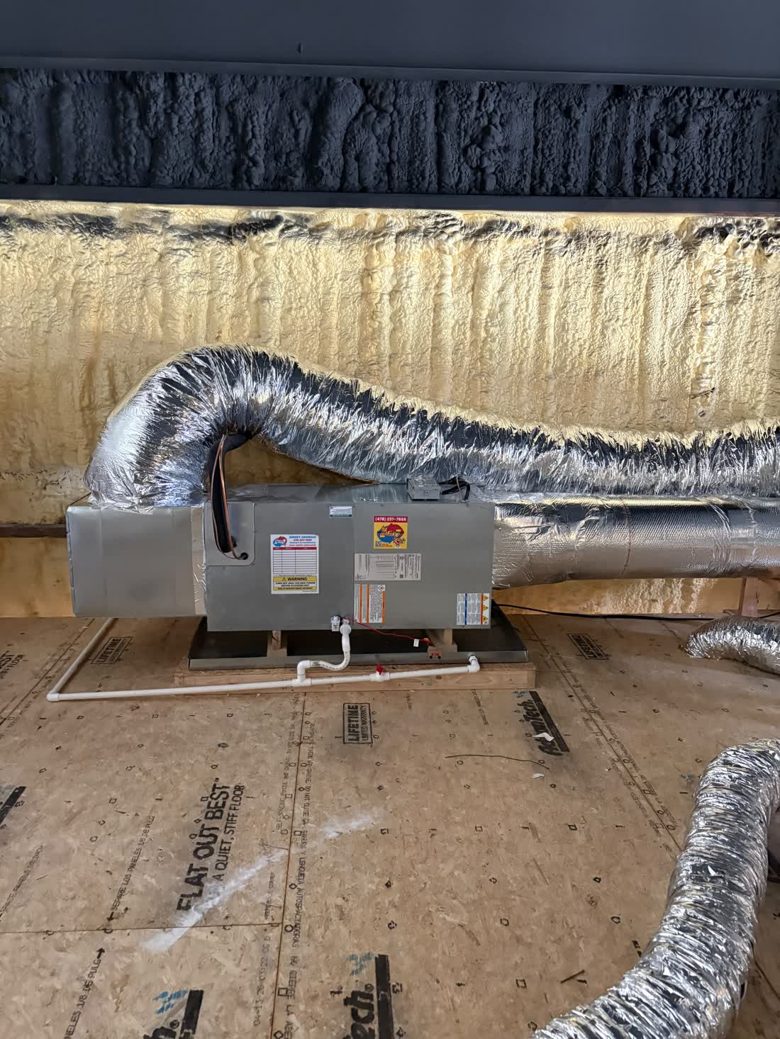 Newly installed air handler with a Sweet Georgia Heating and Air service tag in a spray-foam insulated crawlspace