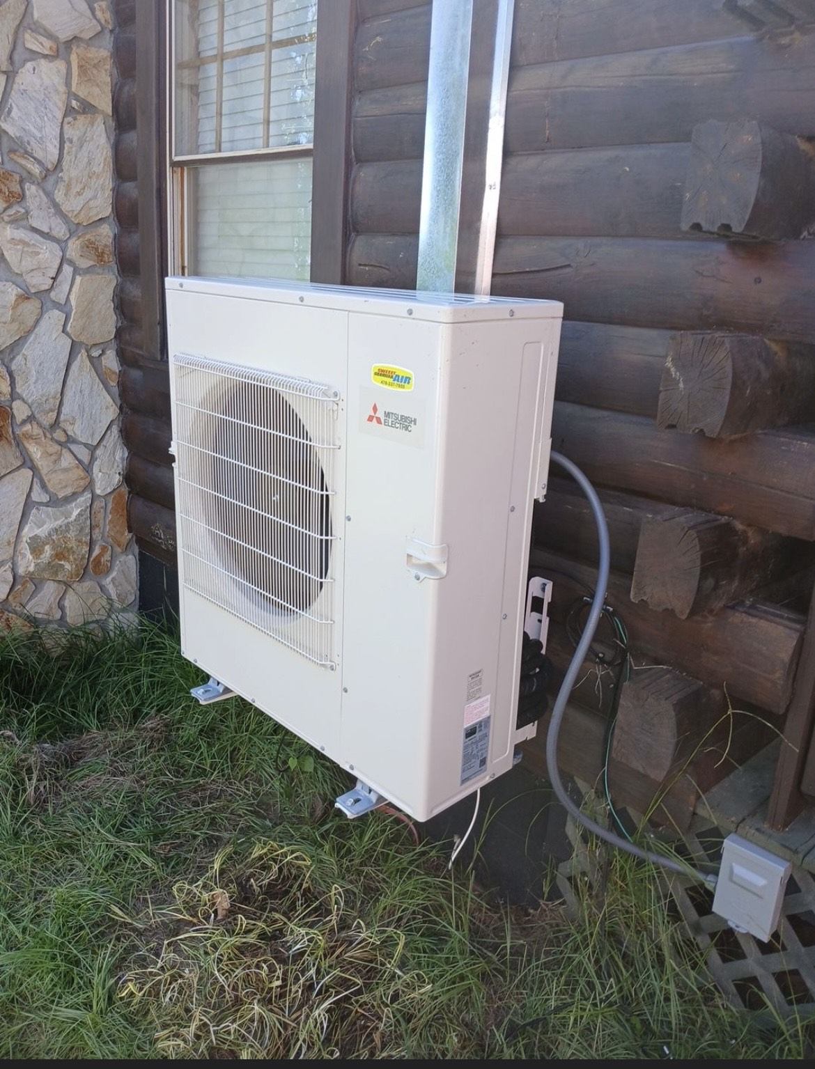 Mitsubishi Electric ductless mini-split heat pump installed on a log cabin exterior